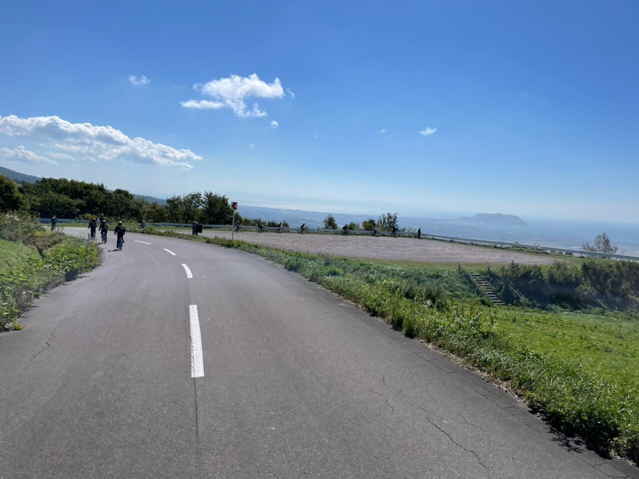 七飯町にある城岱牧場からの眺望を楽しみ、自転車で走る千葉商科大学の学生たち